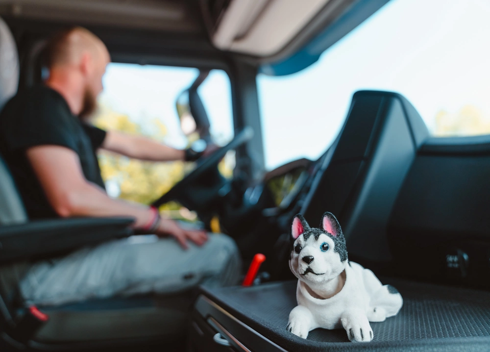 Wackel-Husky steht neben LKW-Fahrer in der Fahrerkabine